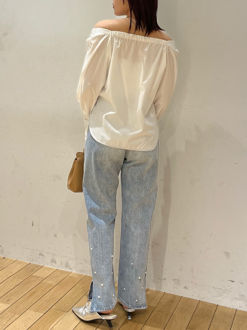 ブルー系のデニムパンツ、シルバー系のサンダル、ブラウン系のハンドバッグを着用したレディースの春コーディネートの3枚目の写真