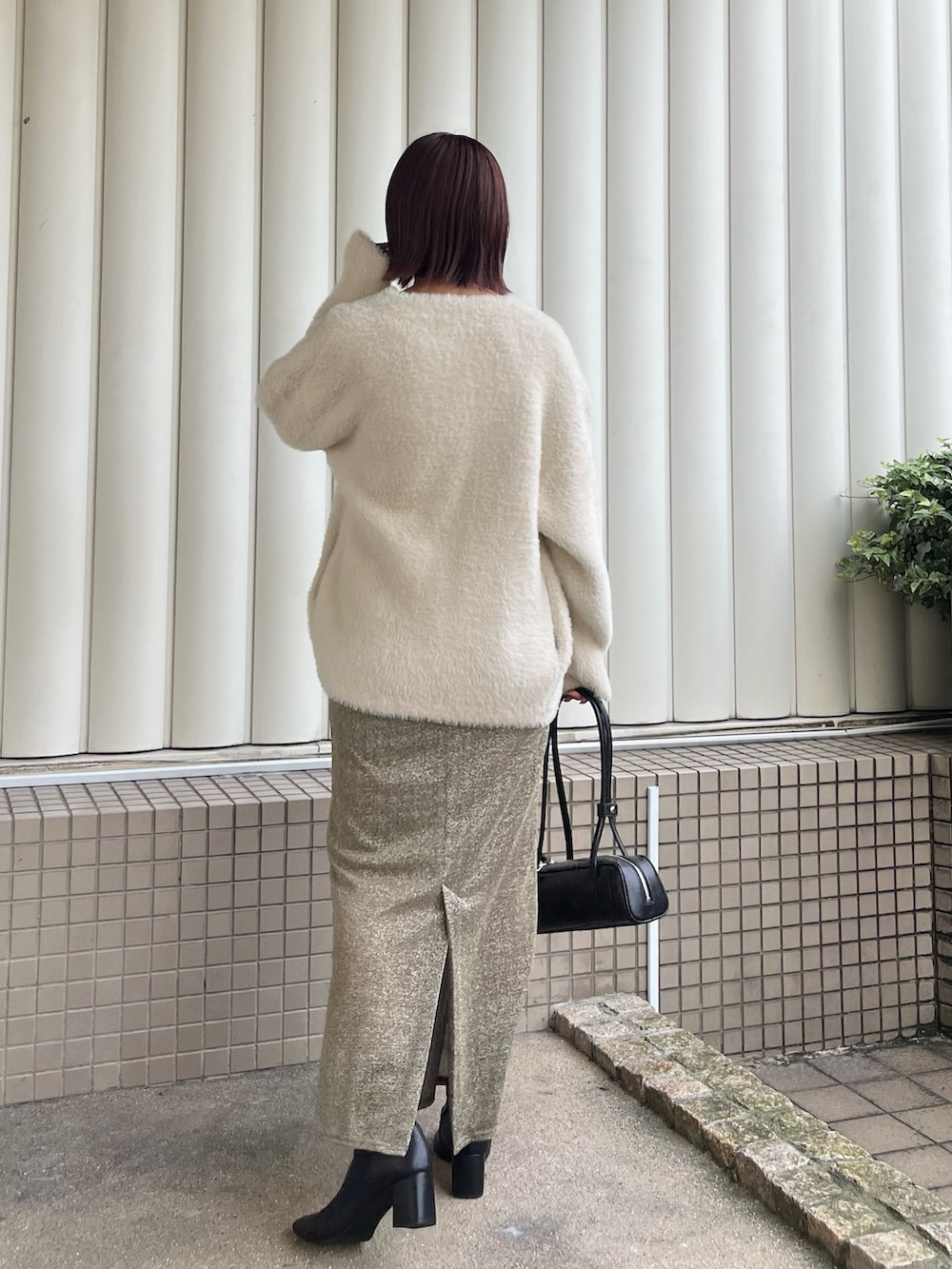 ホワイト系のカーディガン/ボレロ、ゴールド系のスカート、ブラック系のニット/セーターを着用したレディースの冬コーディネートの3枚目の写真