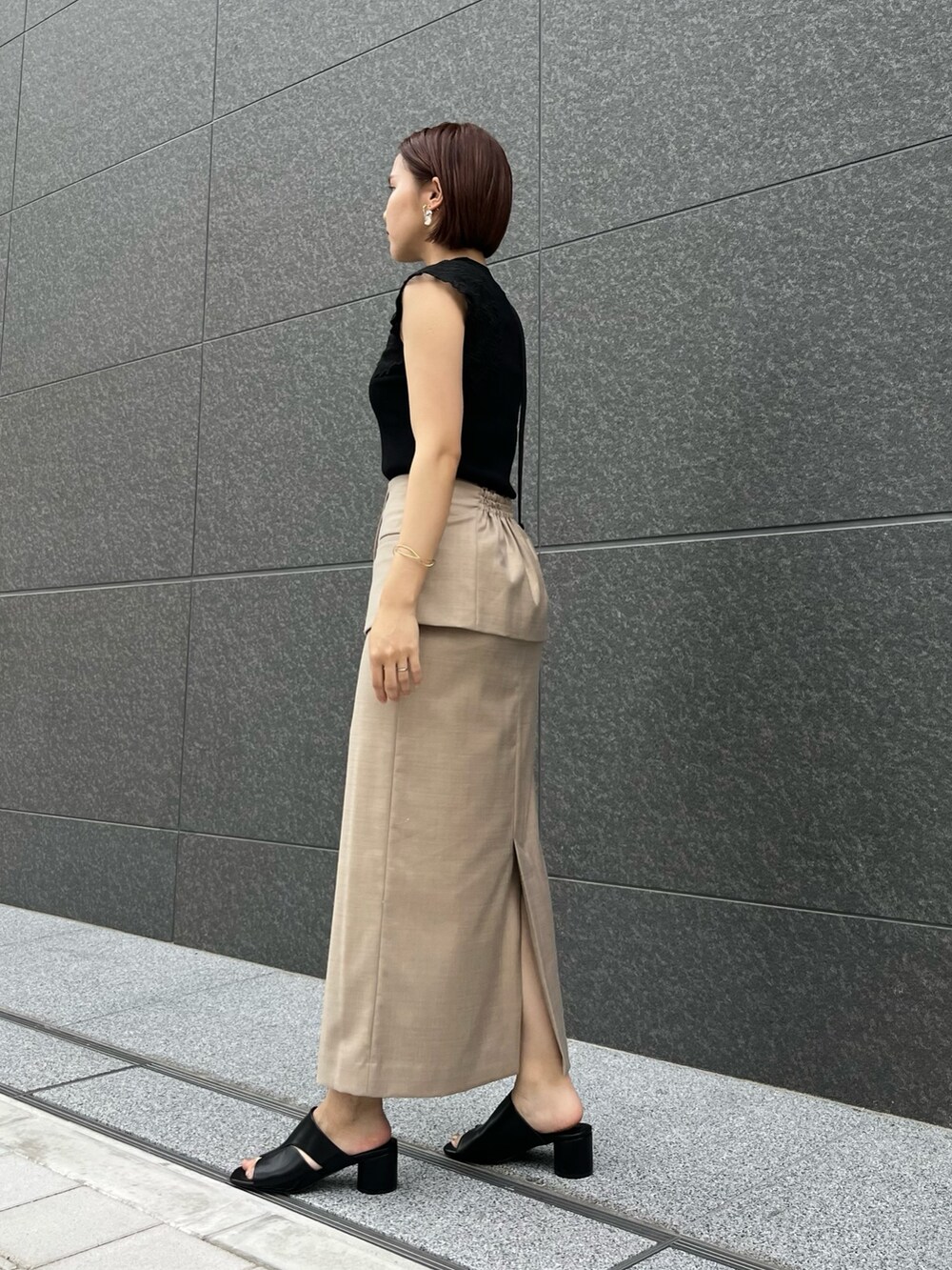 ブラック系のサンダル、ブラック系のニット/セーター、ベージュ系のスカートを着用したレディースの春コーディネートの3枚目の写真