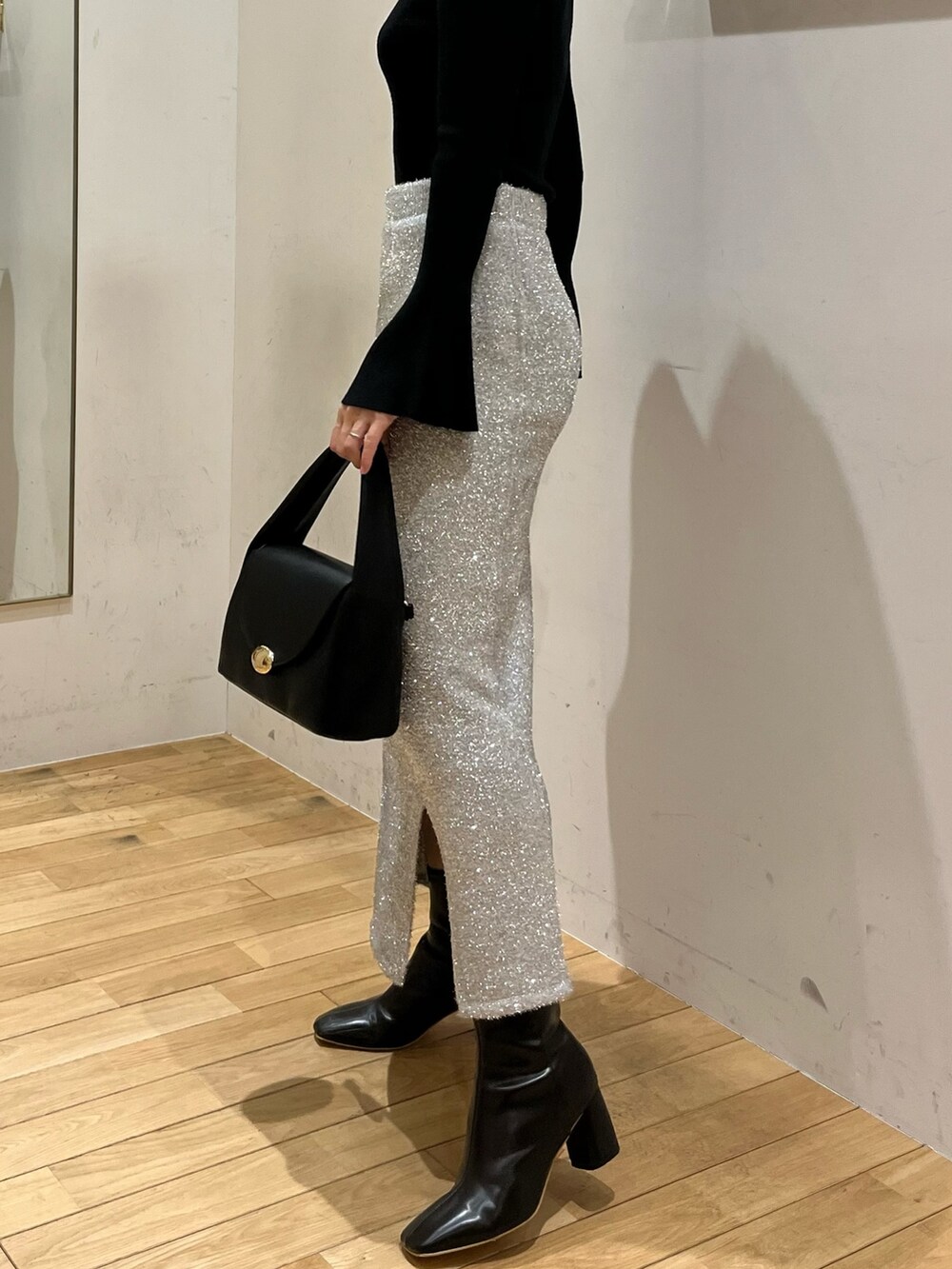 ブラック系のブーツ、ブラック系のハンドバッグ、シルバー系のスカートを着用したレディースの冬コーディネートの5枚目の写真