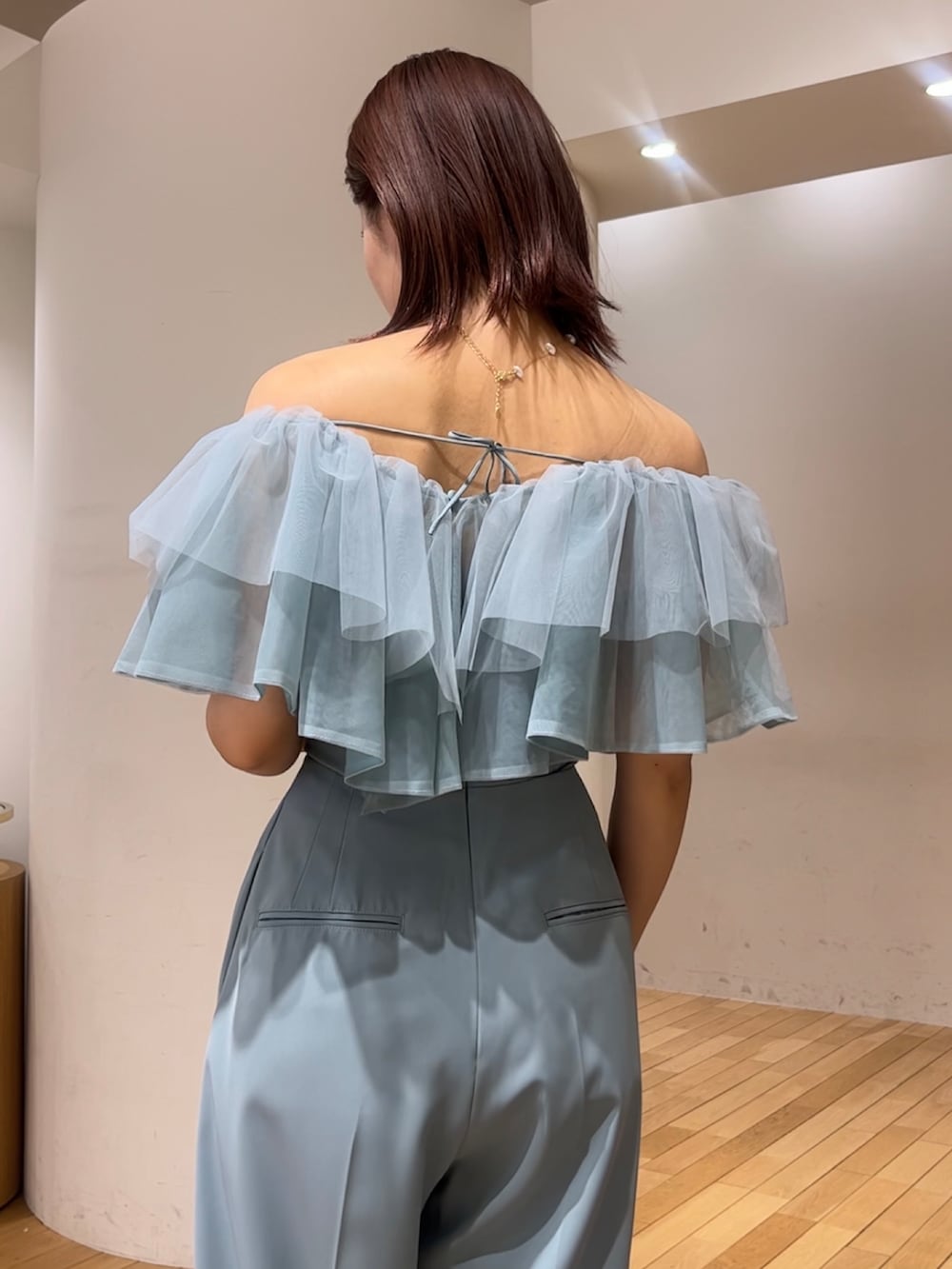 シルバー系のショルダーバッグ、ブラック系のパンプス、ブルー系のパンツドレスを着用したレディースの春コーディネートの6枚目の写真
