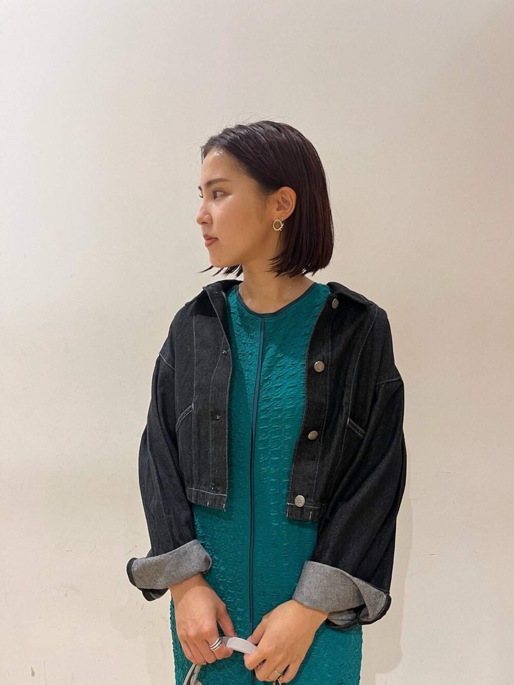 グリーン系のワンピース、ホワイト系のハンドバッグ、ブラック系のデニムジャケットを着用したレディースの夏コーディネートの4枚目の写真