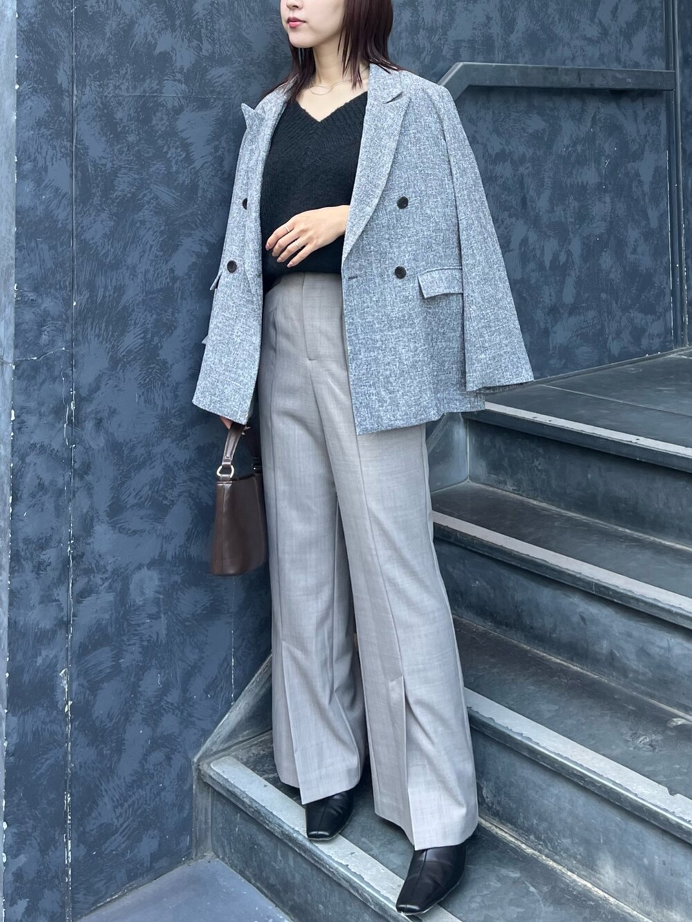 ブラック系のニット/セーター、ブラウン系のハンドバッグ、ブラック系のブーツを着用したレディースの冬コーディネートの4枚目の写真