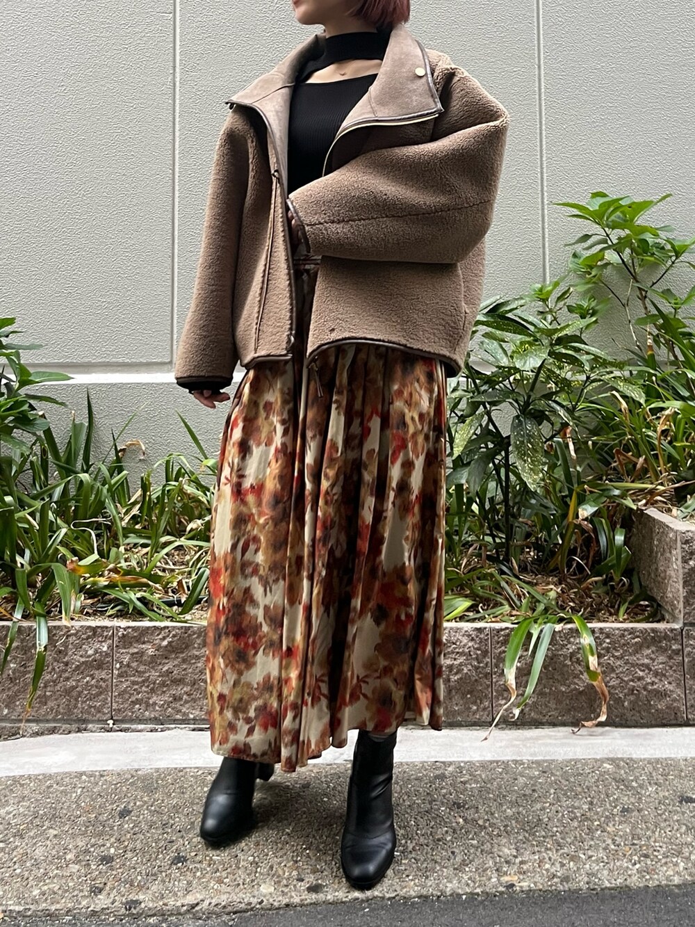 オレンジ系のスカート、ベージュ系のムートンコート、ブラック系のニット/セーターを着用したレディースの秋コーディネートの4枚目の写真