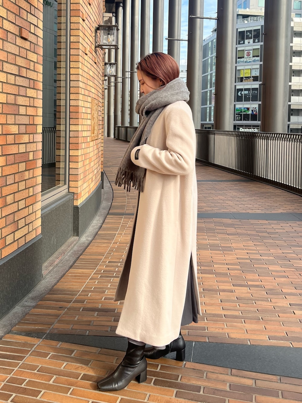 ホワイト系のノーカラーコート、ブラック系のワンピース、グレー系のショルダーバッグを着用したレディースの冬コーディネートの3枚目の写真