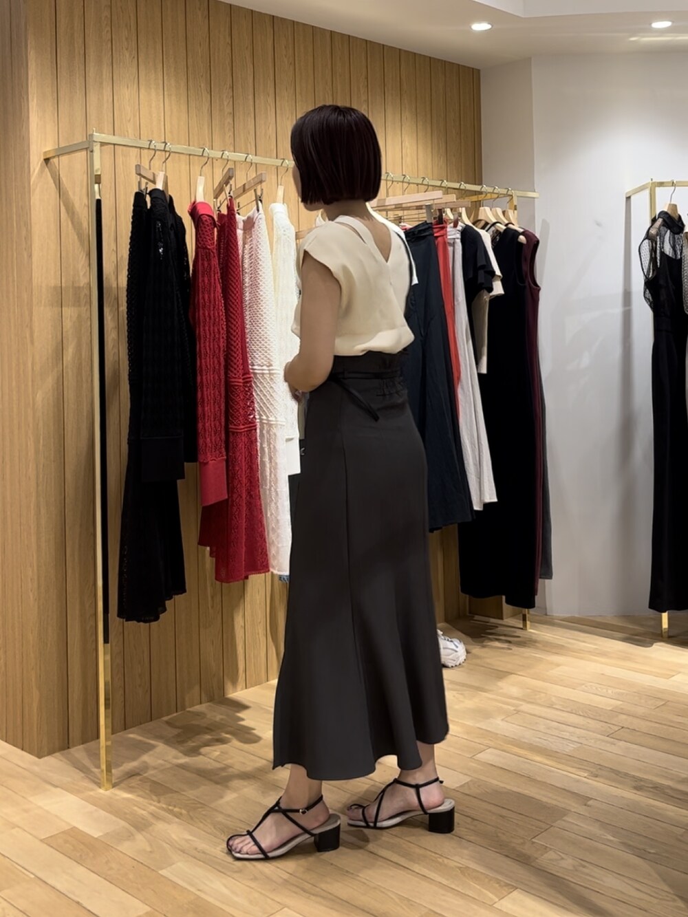 ブラック系のショルダーバッグ、ブラック系のサンダル、ホワイト系のニット/セーターを着用したレディースの夏コーディネートの2枚目の写真