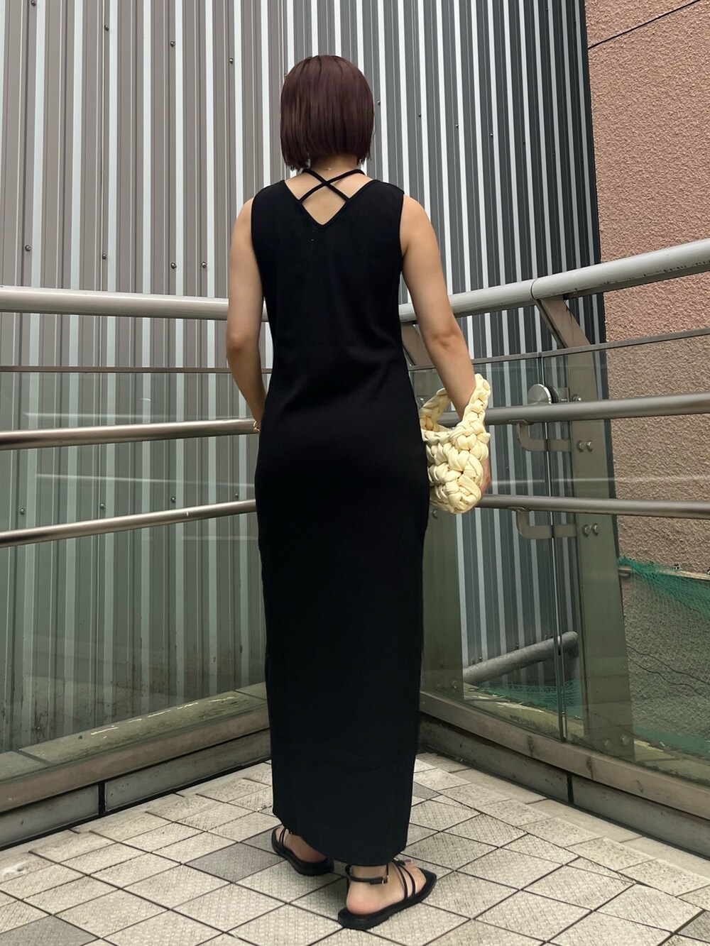 ブラック系のワンピース、ブラック系のサンダル、ホワイト系のハンドバッグを着用したレディースの夏コーディネートの3枚目の写真