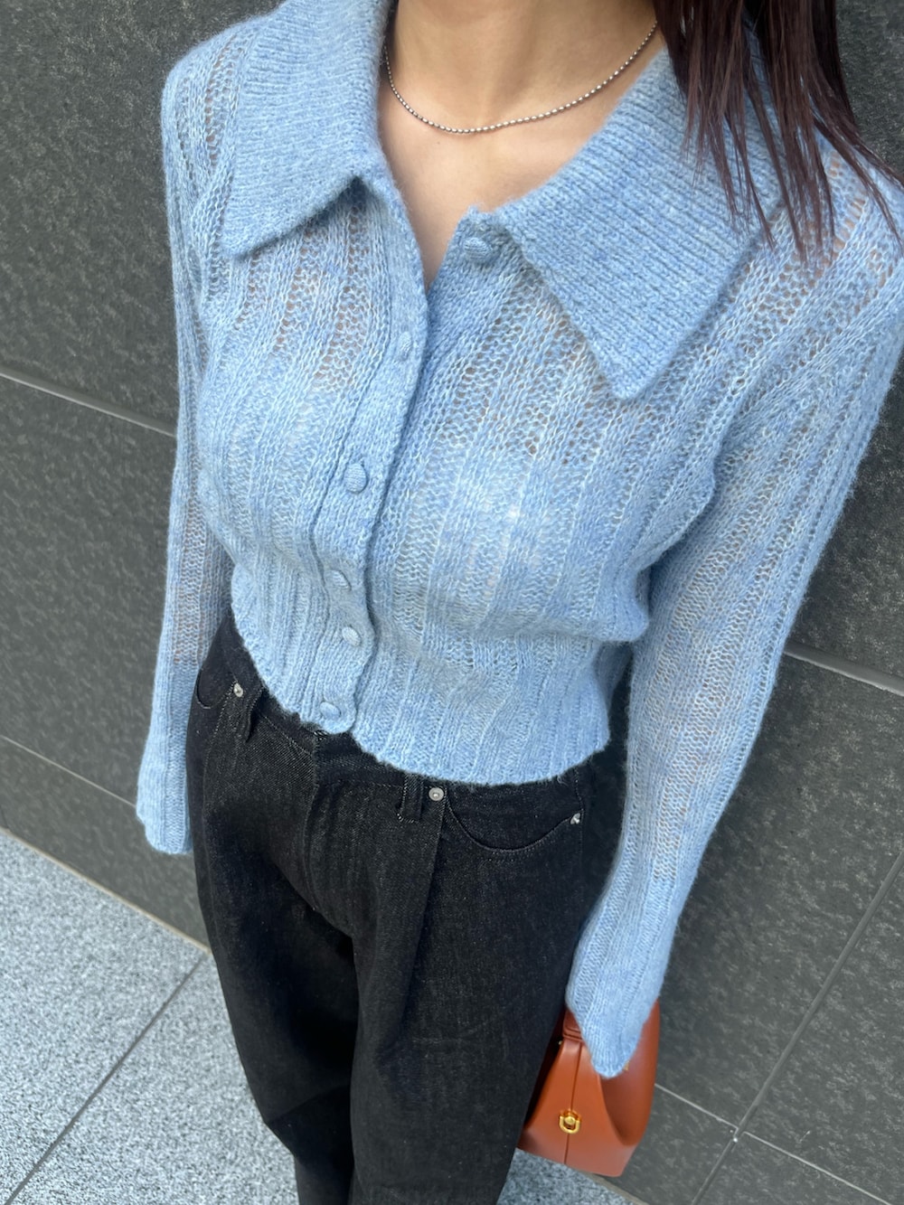 ブルー系のニット/セーター、ブラック系のデニムパンツ、ブラウン系のハンドバッグを着用したレディースの秋コーディネートの7枚目の写真