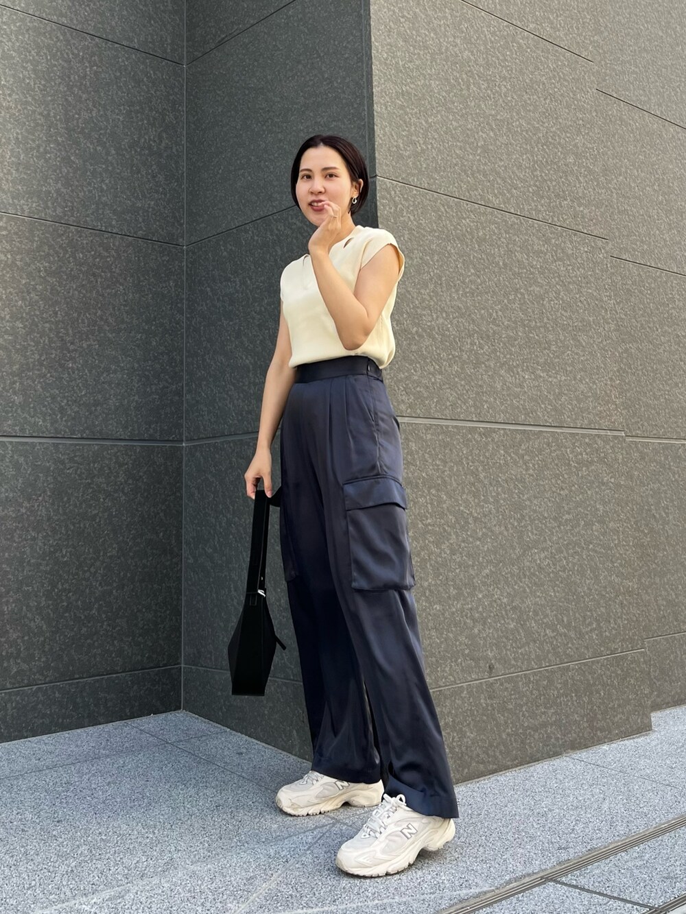 ブラック系のハンドバッグ、ブルー系のカーゴパンツ、ホワイト系のニット/セーターを着用したレディースの春コーディネートの2枚目の写真