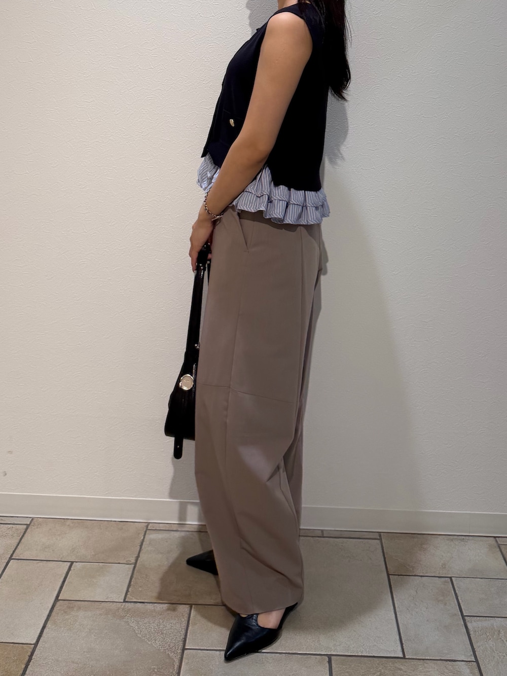ベージュ系のその他パンツ、ブルー系のニット/セーター、ブラック系のハンドバッグを着用したレディースの夏コーディネートの2枚目の写真