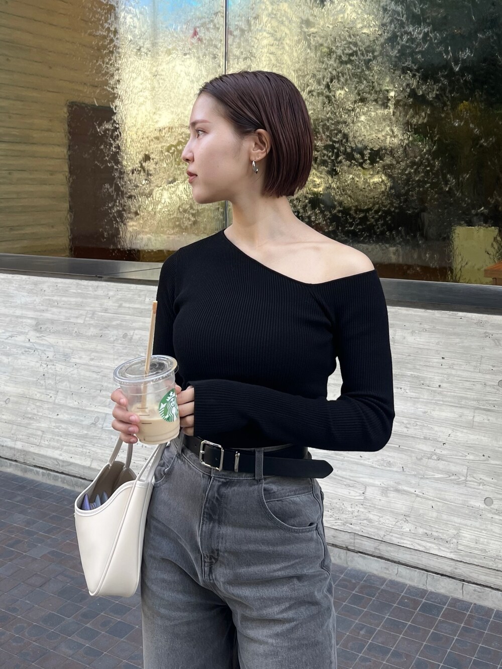 グレー系のデニムパンツ、ブラック系のニット/セーター、ブラック系のベルトを着用したレディースの春コーディネートの4枚目の写真