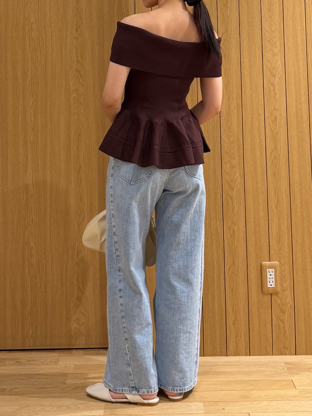 ブラウン系のニット/セーター、ブルー系のデニムパンツ、ホワイト系のハンドバッグを着用したレディースの夏コーディネートの3枚目の写真