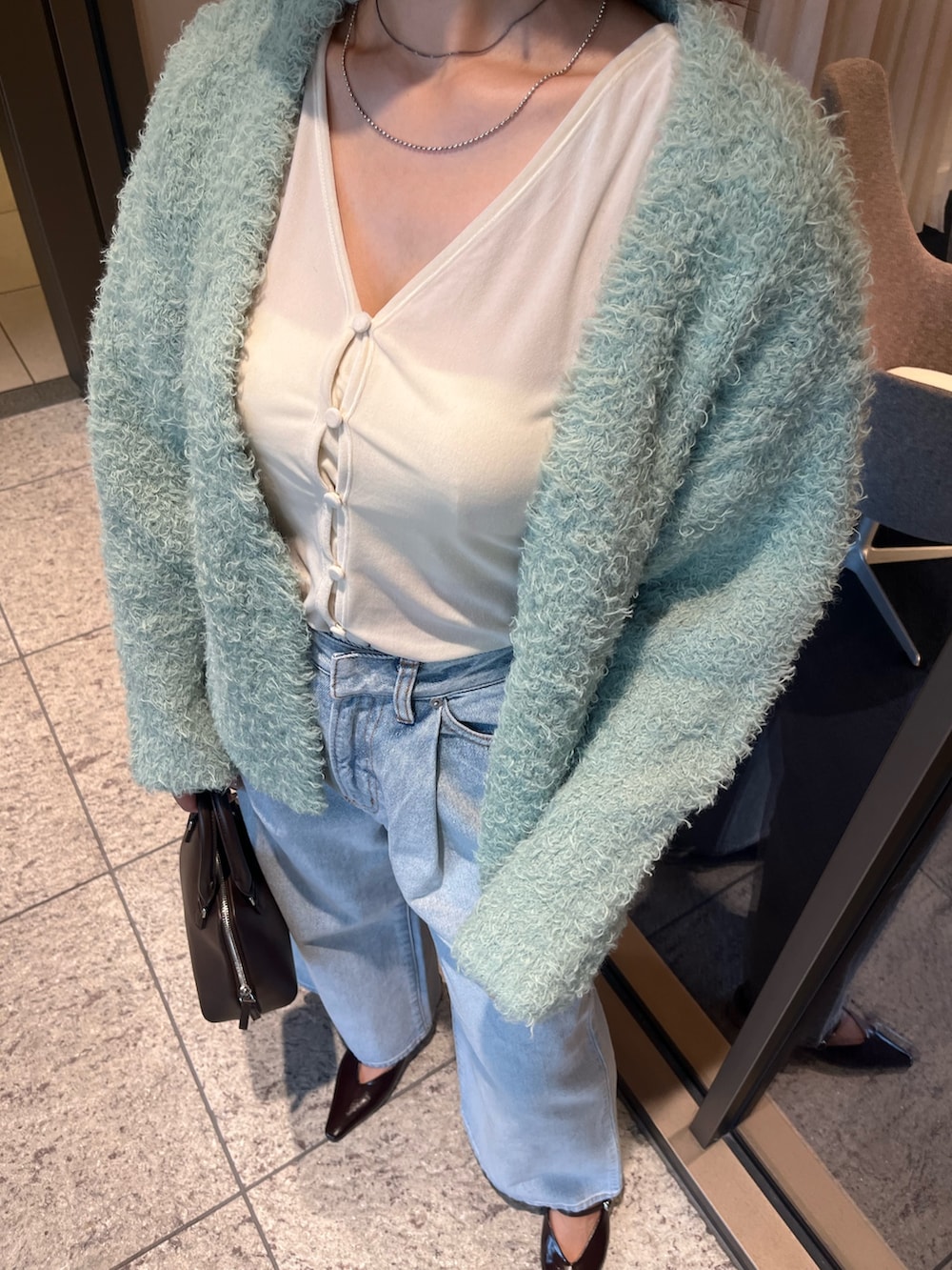 ブルー系のデニムパンツ、ブラウン系のパンプス、ブラウン系のボストンバッグを着用したレディースの夏コーディネートの7枚目の写真