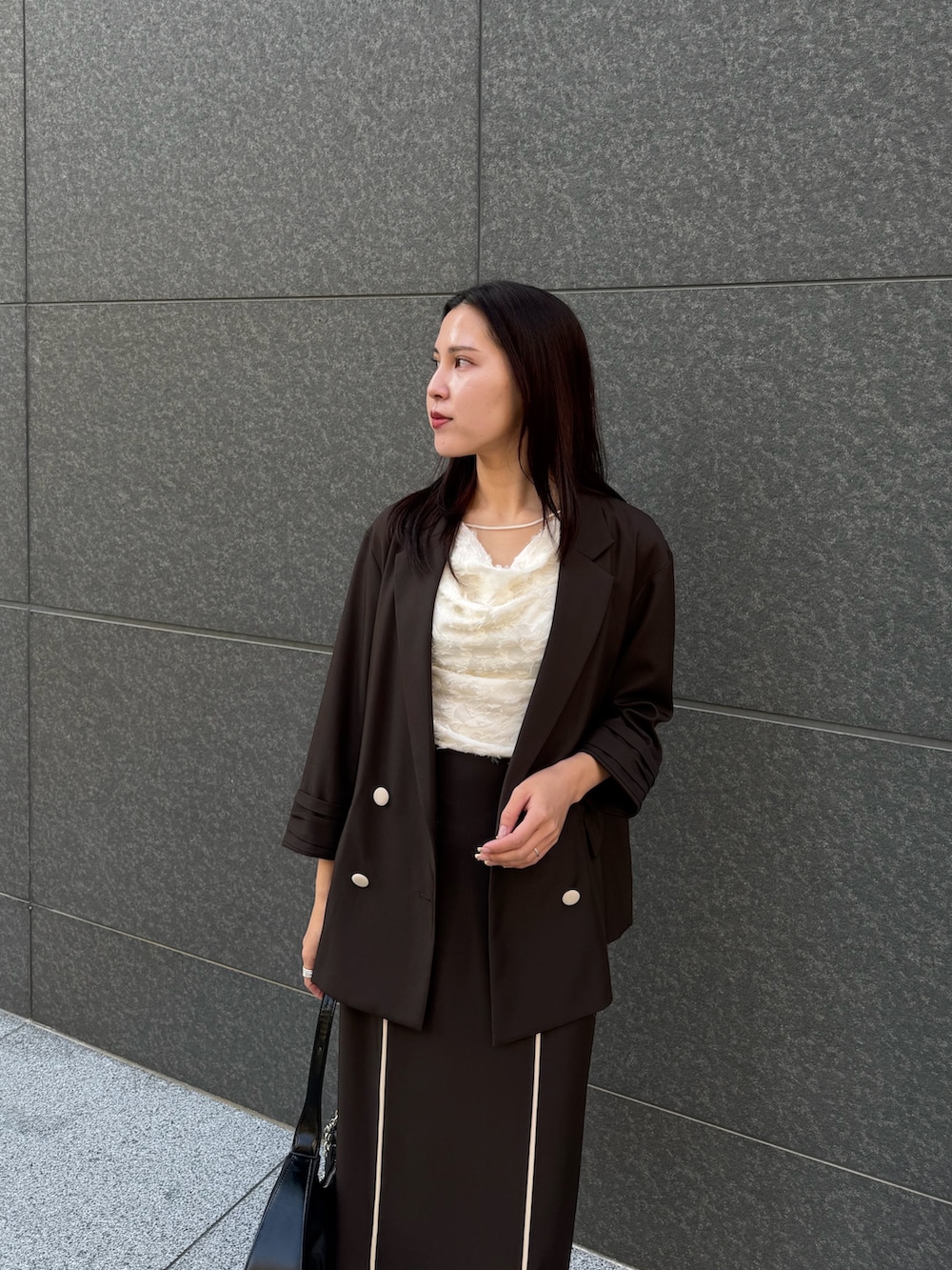 ブラウン系のテーラードジャケット、ホワイト系のシャツ/ブラウス、ブラウン系のスカートを着用したレディースの春コーディネートの4枚目の写真