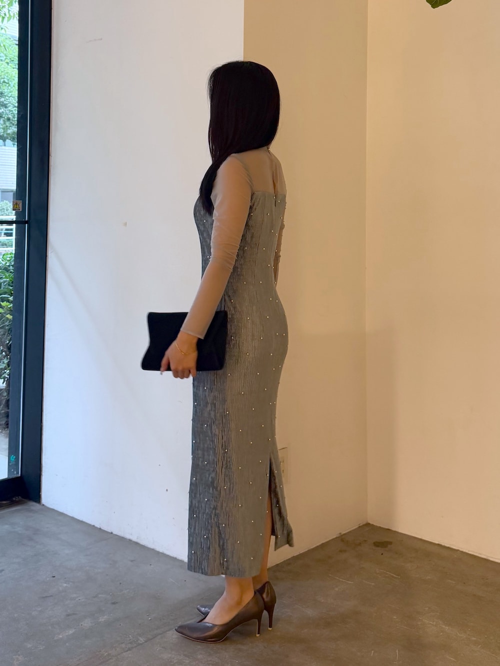 ブラック系のクラッチバッグ、ブルー系のドレス、シルバー系のパンプスを着用したレディースの夏コーディネートの2枚目の写真