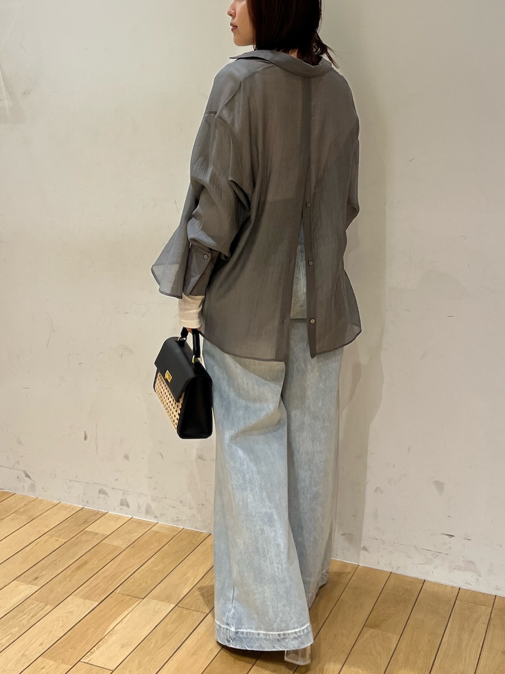 ホワイト系のサンダル、ブラック系のハンドバッグ、ブルー系のデニムパンツを着用したレディースの春コーディネートの3枚目の写真