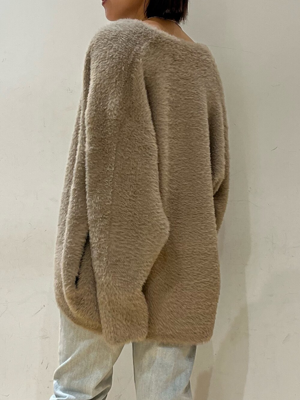 ブルー系のデニムパンツ、ホワイト系のニット/セーター、ブラウン系のカーディガン/ボレロを着用したレディースの秋コーディネートの5枚目の写真