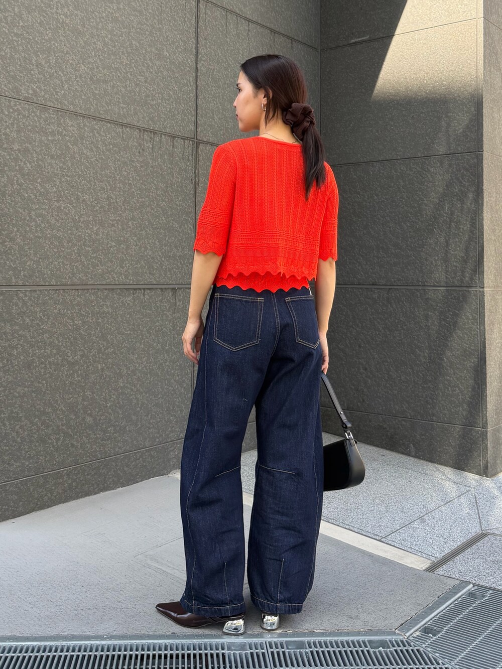 ブルー系のデニムパンツ、オレンジ系のアンサンブルを着用したレディースの春コーディネートの3枚目の写真