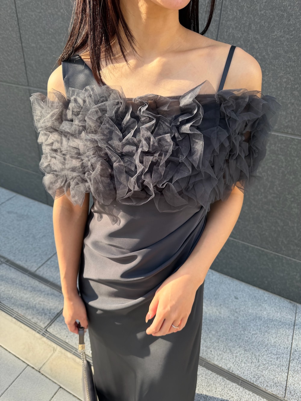 シルバー系のクラッチバッグ、シルバー系のパンプス、グレー系のドレスを着用したレディースの冬コーディネートの7枚目の写真