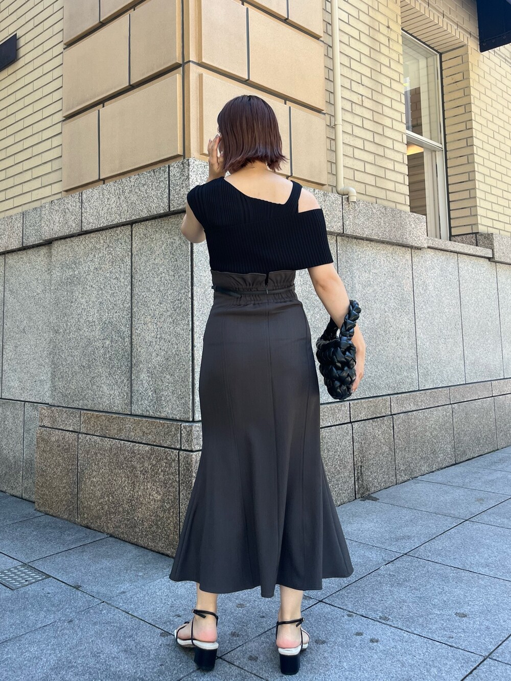 グレー系のスカート、ブラック系のサンダル、ブラック系のハンドバッグを着用したレディースの夏コーディネートの3枚目の写真