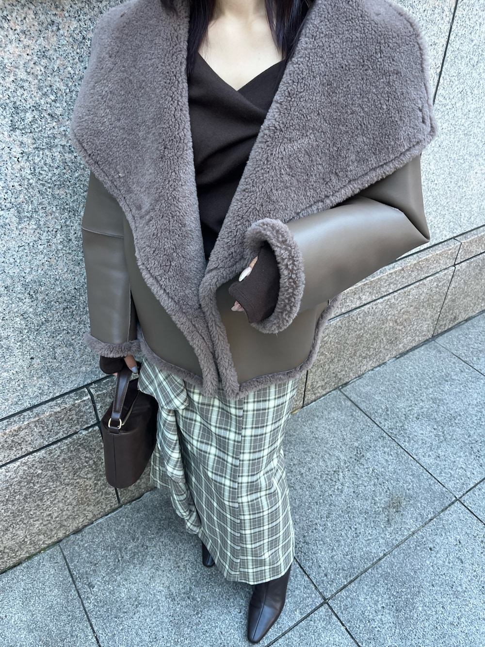 ベージュ系のムートンコート、ブラウン系のTシャツ/カットソー、ブラウン系のスカートを着用したレディースの冬コーディネートの5枚目の写真