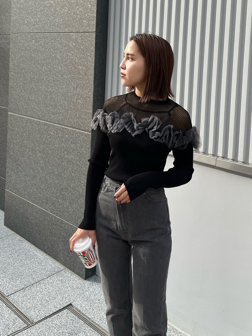 ブラック系のデニムパンツ、ブラック系のニット/セーターを着用したレディースの秋コーディネートの3枚目の写真