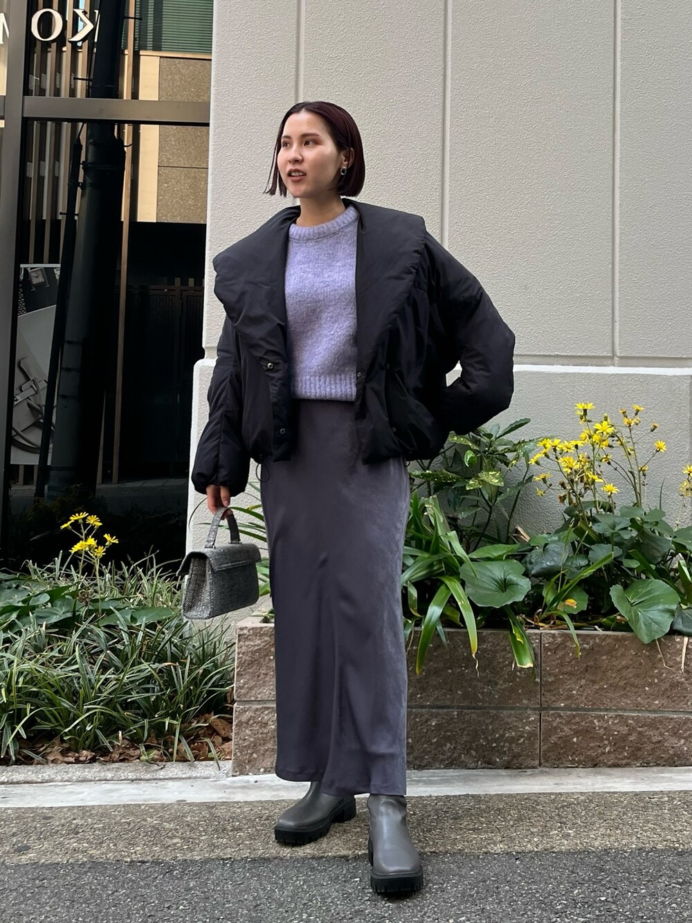 グレー系のスカート、パープル系のニット/セーター、ブラック系のダウンジャケット/コートを着用したレディースの冬コーディネートの4枚目の写真