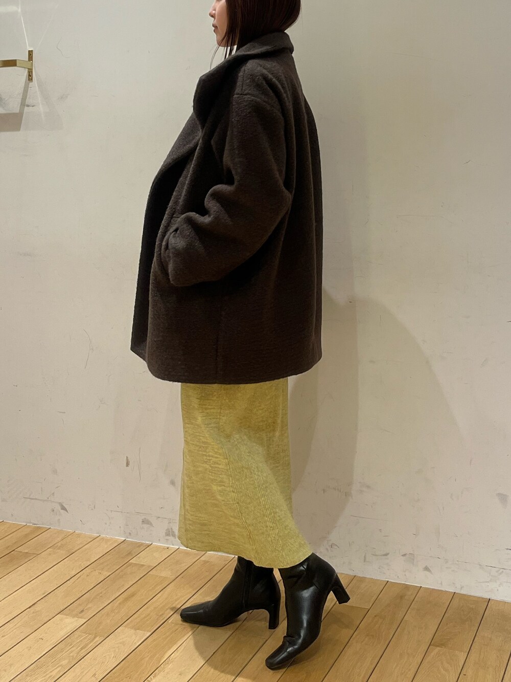 ブラウン系のその他アウター、グリーン系のワンピース、ブラック系のブーツを着用したレディースの冬コーディネートの2枚目の写真