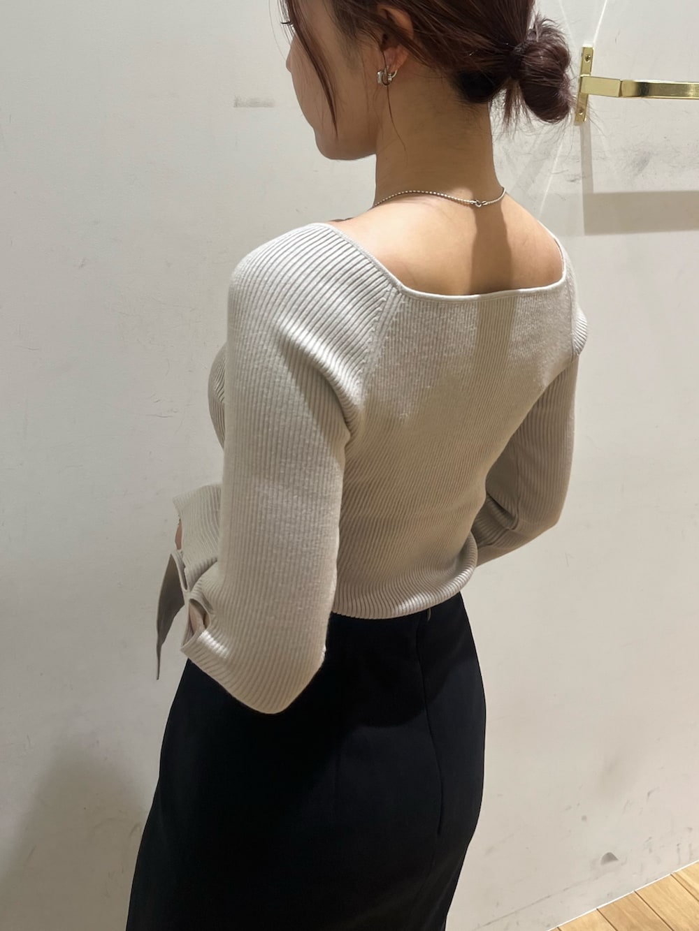 ブラック系のスカート、ベージュ系のニット/セーター、ブラウン系のハンドバッグを着用したレディースの秋コーディネートの5枚目の写真