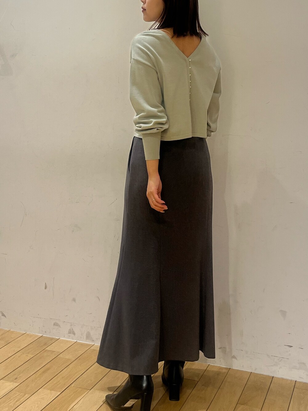 グリーン系のニット/セーター、グレー系のスカート、ブラック系のブーツを着用したレディースの冬コーディネートの3枚目の写真