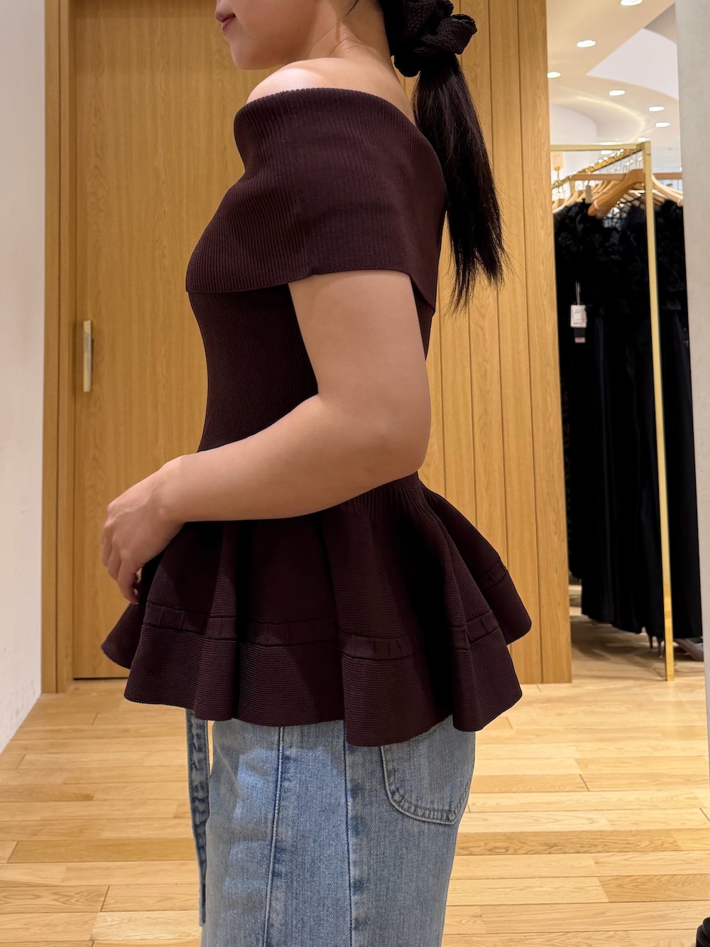 ブラウン系のニット/セーター、ブルー系のデニムパンツ、ホワイト系のハンドバッグを着用したレディースの夏コーディネートの6枚目の写真