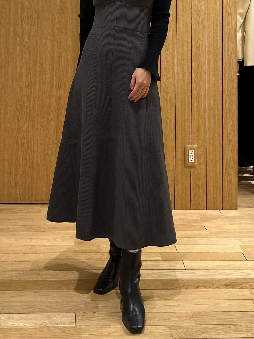 ブラック系のブーツ、ブラック系のニット/セーター、グレー系のジャンパースカートを着用したレディースの冬コーディネートの5枚目の写真