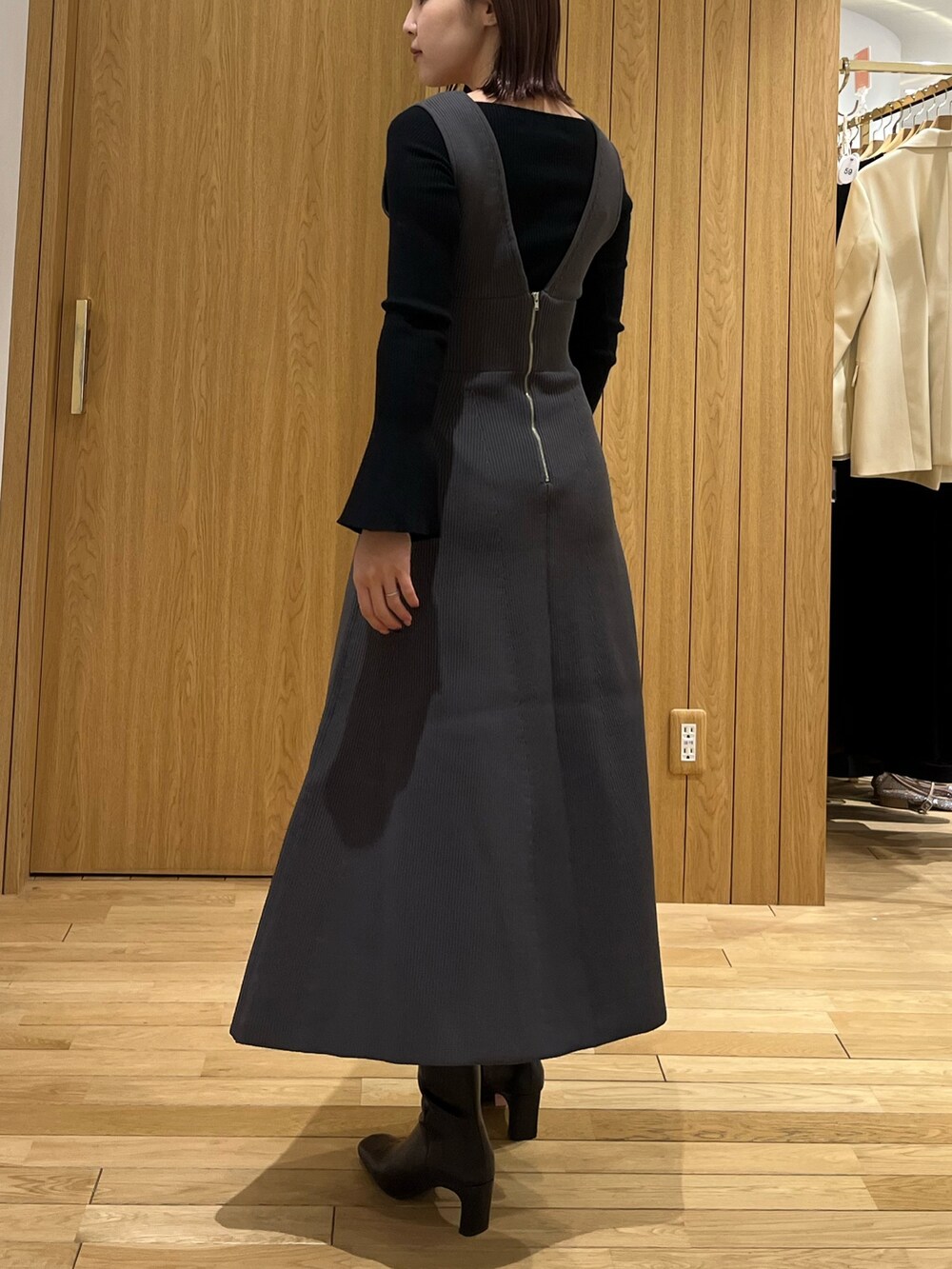 ブラック系のブーツ、ブラック系のニット/セーター、グレー系のジャンパースカートを着用したレディースの冬コーディネートの3枚目の写真