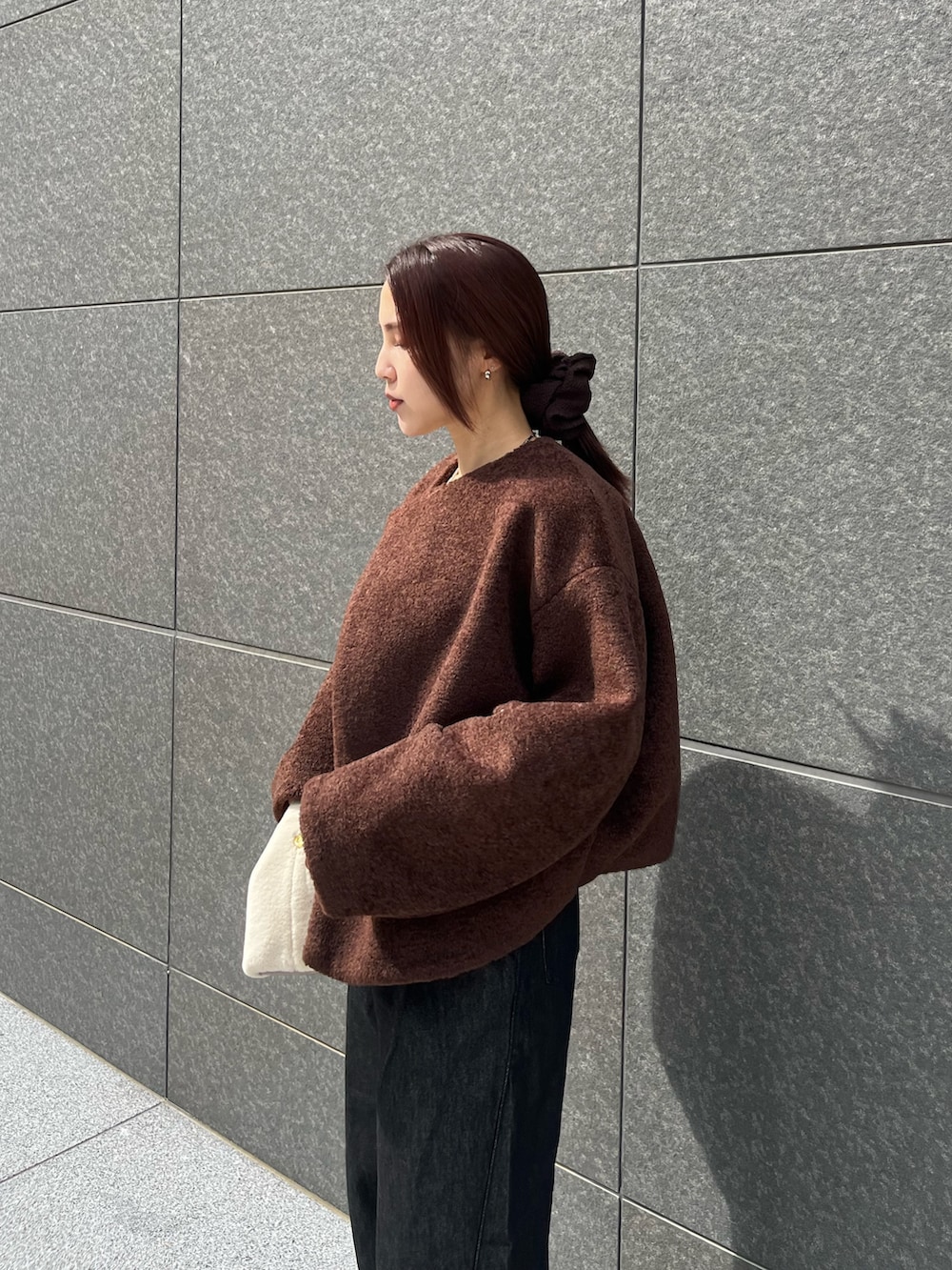 ブラック系のデニムパンツ、ホワイト系のハンドバッグ、ブラウン系のTシャツ/カットソーを着用したレディースの秋コーディネートの6枚目の写真