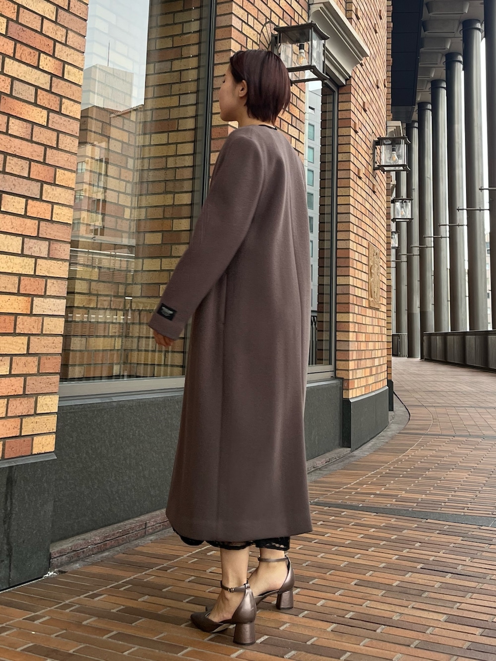 ブラック系のドレス、その他のパンプス、シルバー系のハンドバッグを着用したレディースの冬コーディネートの2枚目の写真