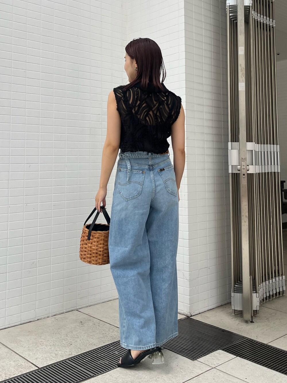 ブラウン系のハンドバッグ、ブラック系のサンダル、ブラック系のシャツ/ブラウスを着用したレディースの夏コーディネートの3枚目の写真