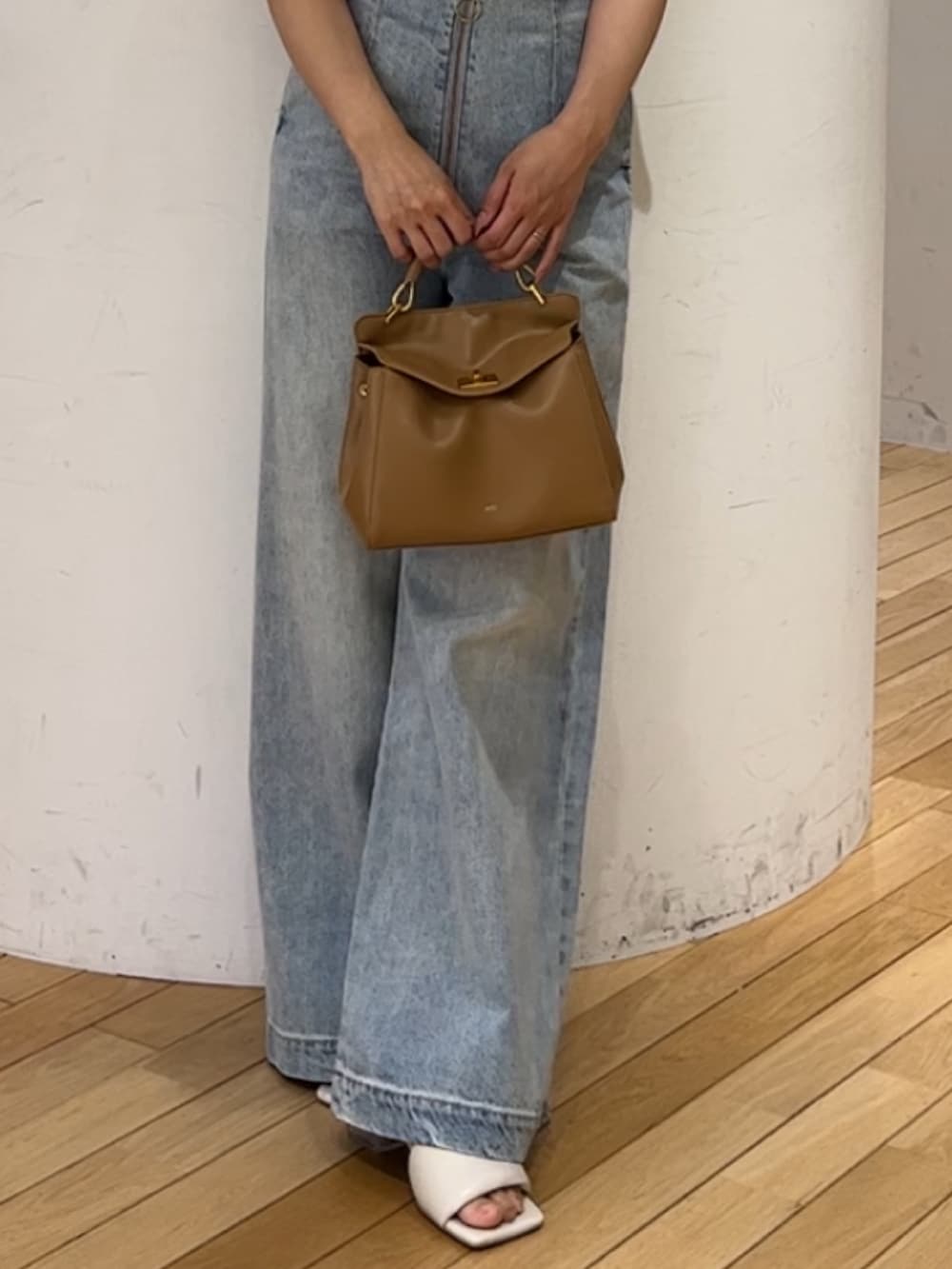 ブルー系のデニムパンツ、ホワイト系のサンダル、ブラウン系のハンドバッグを着用したレディースの春コーディネートの7枚目の写真