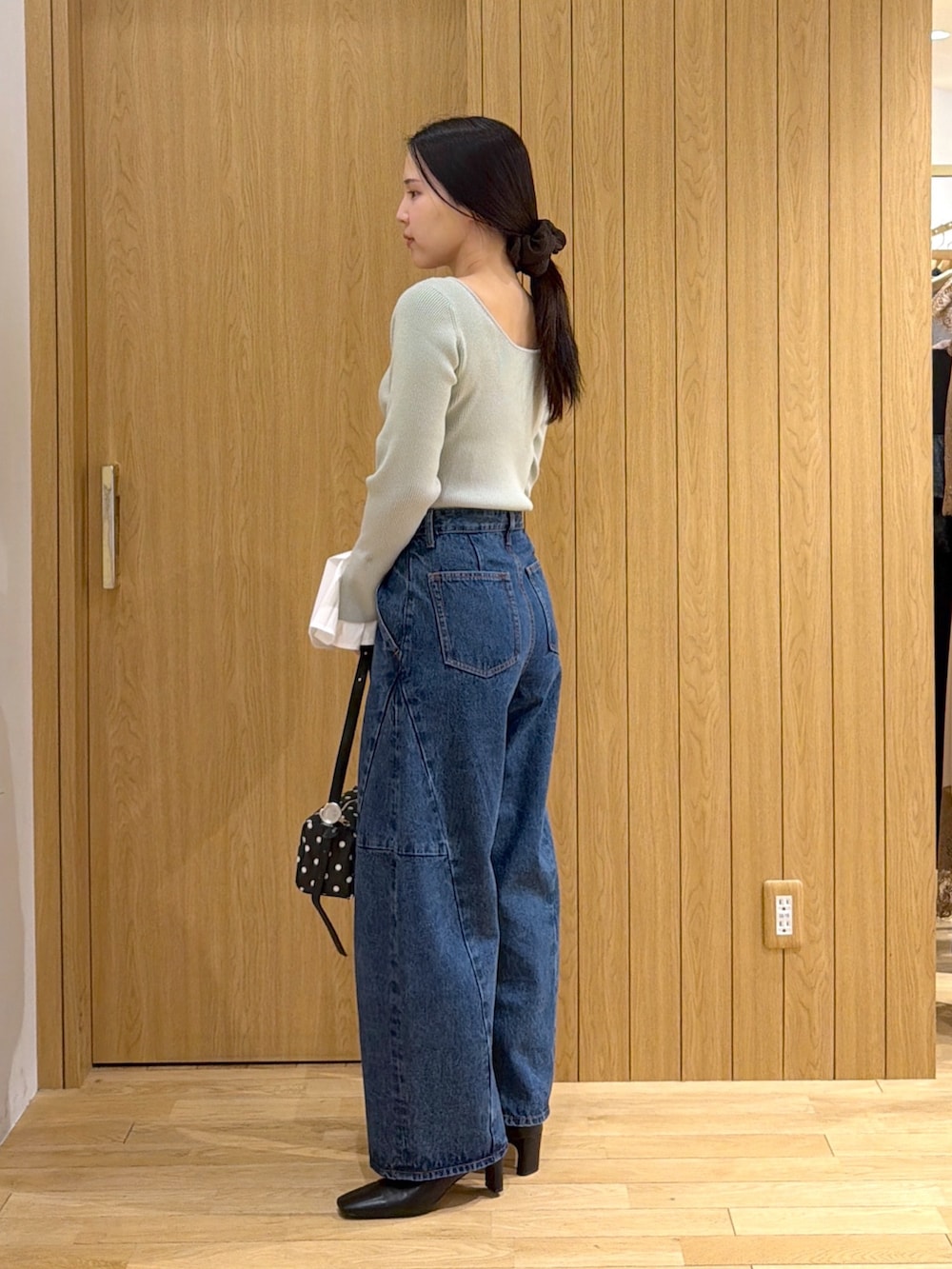 ブルー系のデニムパンツ、ブラック系のブーツ、ブラック系のハンドバッグを着用したレディースの秋コーディネートの2枚目の写真