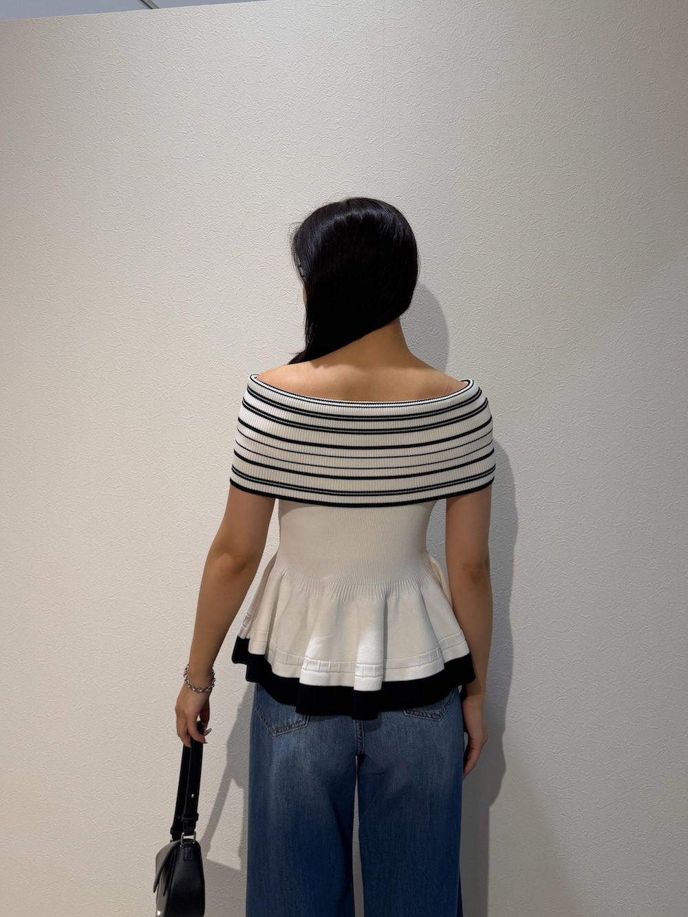 ブルー系のデニムパンツ、ブラック系のハンドバッグ、グリーン系のパンプスを着用したレディースの夏コーディネートの6枚目の写真
