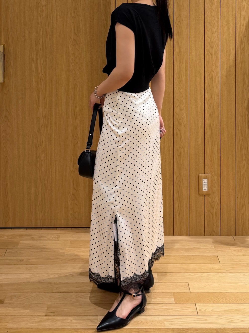 ブラック系のパンプス、ブラック系のニット/セーター、ホワイト系のスカートを着用したレディースの夏コーディネートの2枚目の写真