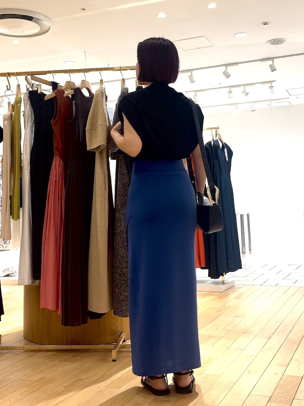 ブルー系のスカート、ブラック系のニット/セーター、ブラック系のショルダーバッグを着用したレディースの夏コーディネートの3枚目の写真