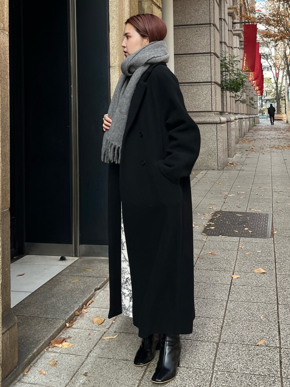 ホワイト系のワンピース、ブラック系のチェスターコート、ブラック系のハンドバッグを着用したレディースの冬コーディネートの2枚目の写真