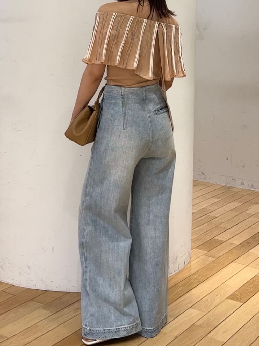ブルー系のデニムパンツ、ホワイト系のサンダル、ブラウン系のハンドバッグを着用したレディースの春コーディネートの3枚目の写真