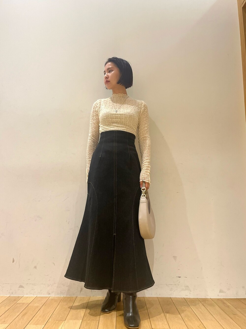 ブラック系のハンドバッグ、ブラック系のデニムスカート、ブラック系のブーツを着用したレディースの秋コーディネートの2枚目の写真