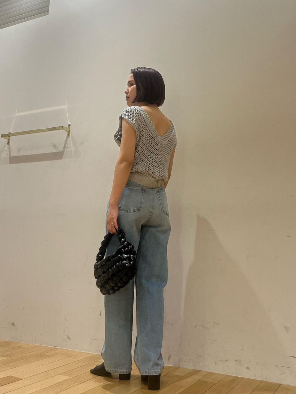 シルバー系のニット/セーター、ブルー系のデニムパンツ、ブラック系のハンドバッグを着用したレディースの夏コーディネートの3枚目の写真