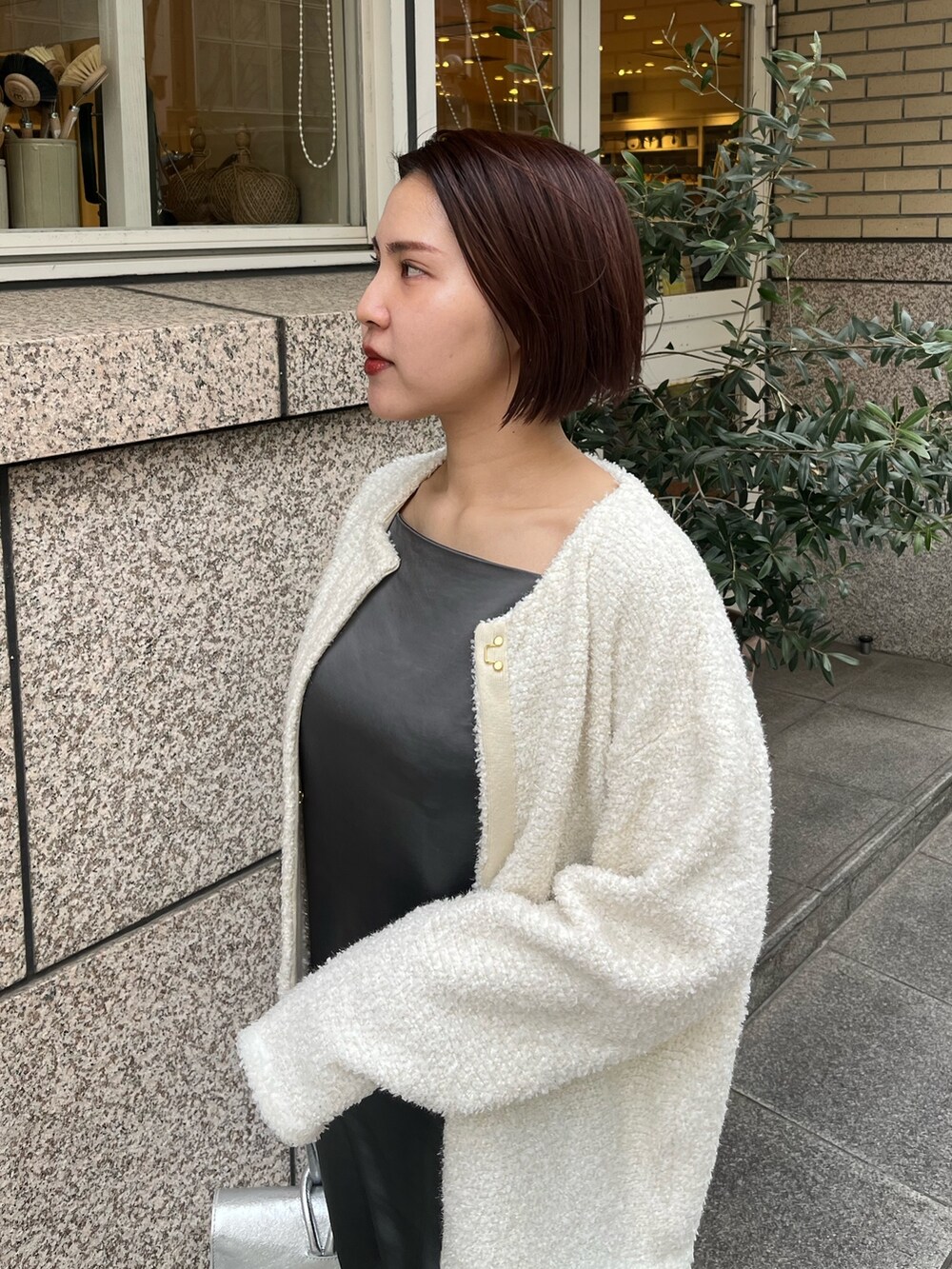 シルバー系のハンドバッグ、ホワイト系のスニーカー、グレー系のワンピースを着用したレディースの春コーディネートの5枚目の写真