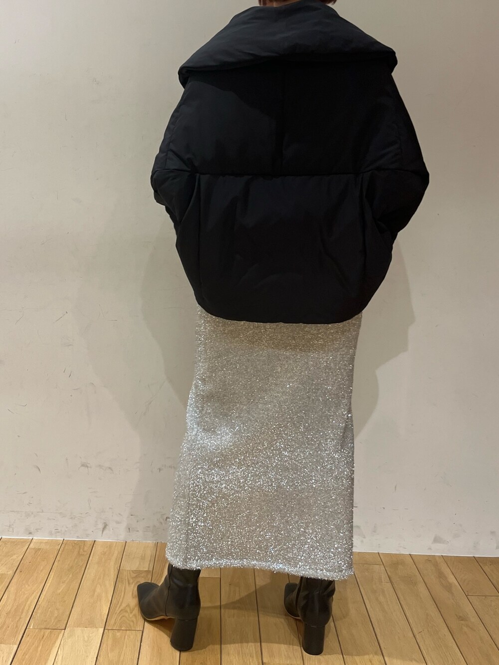 ブラック系のブーツ、ブラック系のハンドバッグ、シルバー系のスカートを着用したレディースの冬コーディネートの4枚目の写真