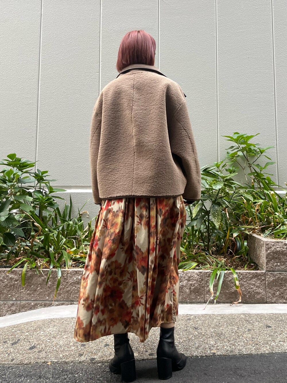 オレンジ系のスカート、ベージュ系のムートンコート、ブラック系のニット/セーターを着用したレディースの秋コーディネートの5枚目の写真