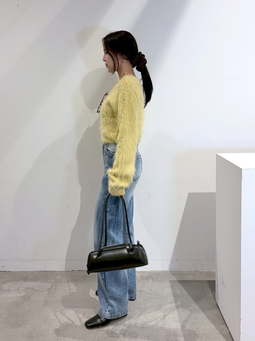 ブルー系のデニムパンツ、ブラック系のブーツ、イエロー系のニット/セーターを着用したレディースの秋コーディネートの2枚目の写真