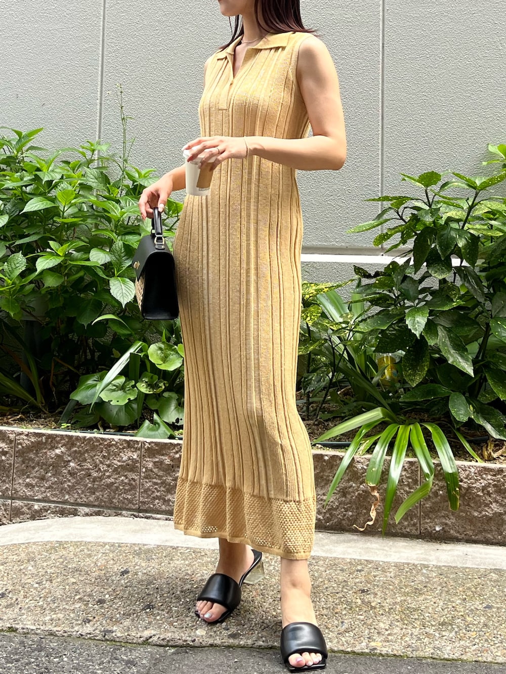 イエロー系のワンピース、ブラック系のハンドバッグ、ブラック系のサンダルを着用したレディースの夏コーディネートの4枚目の写真